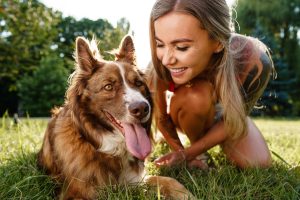 La photo en gros plan d'une jeune femme avec son chien assis sur l'herbe dans le parc